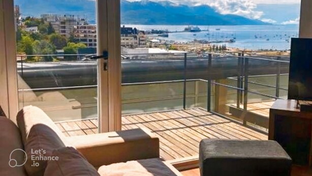 A balcony with a wooden deck, a sofa, and a television. - Duerme Ushuaia (Ushuaia)