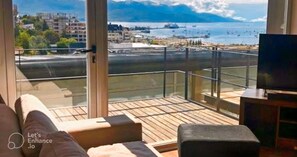 Ein Balkon mit Holzboden, einer Couch und einem Fernseher.