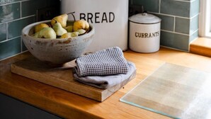 Un plan de travail de cuisine avec un saladier de poires, un rouleau à pâtisserie, une cafetière et un récipient étiqueté « CURRANTS ».