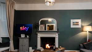Una sala de estar con chimenea, televisor y sofá.