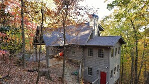 A rustic cabin with a red door, surrounded by autumn foliage. - Enjoy cookouts on the deck and peaceful valley views! - Elemental Bliss (Jasper)