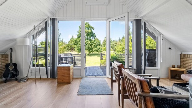 A spacious attic room with a large sliding glass door leading to a garden.