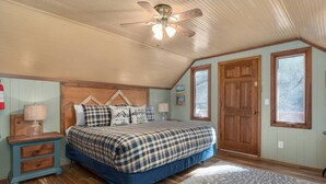 A bedroom with a bed, wooden headboard, two nightstands, a floor lamp, a ceiling fan, and a window.
