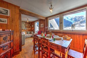 Un interior de madera con una mesa de comedor, sillas y vistas a montañas a través de amplios ventanales.