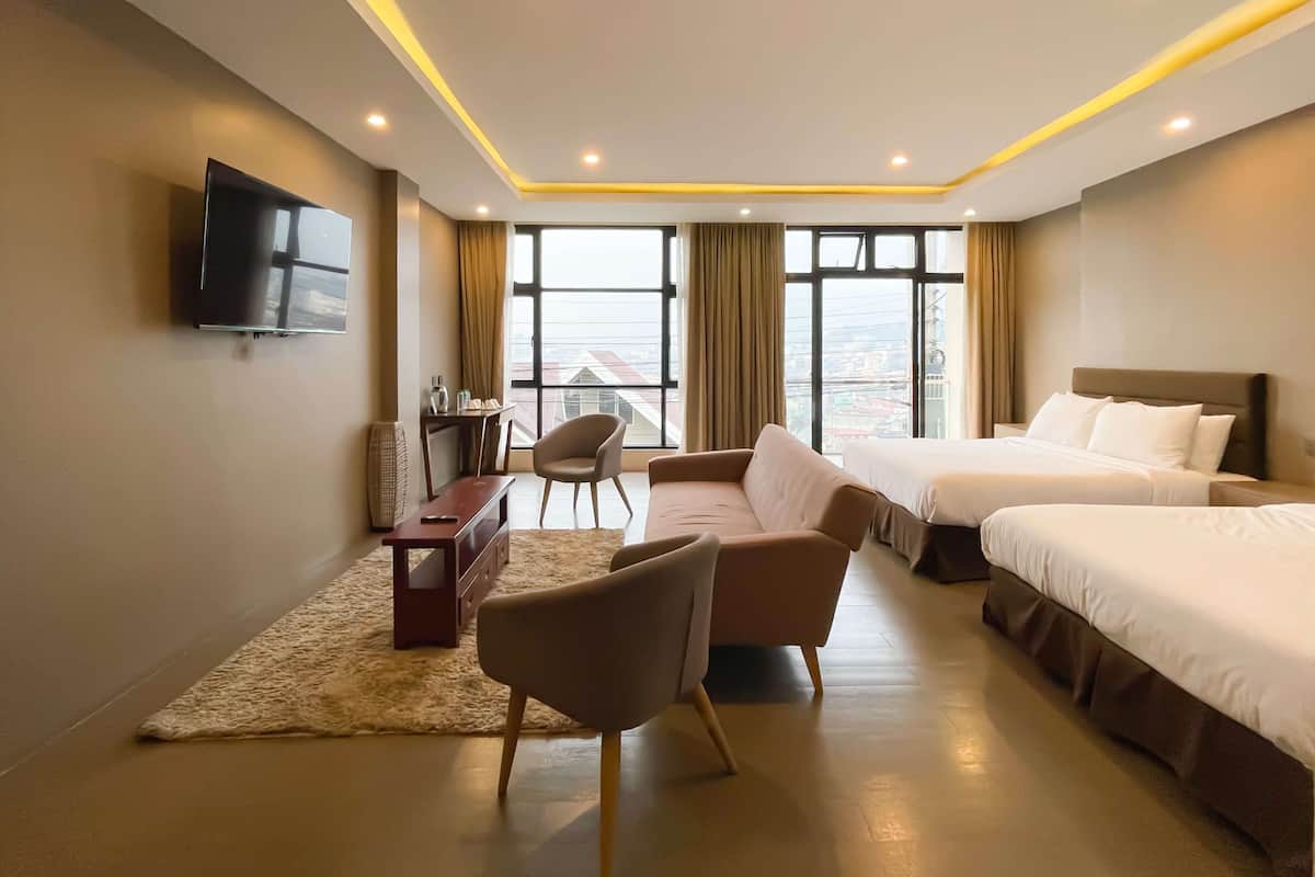 Habitación de hotel con dos camas, un escritorio, una silla y un televisor.