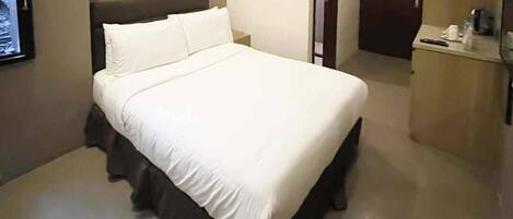 A neatly made bed with white linens in a hotel room.