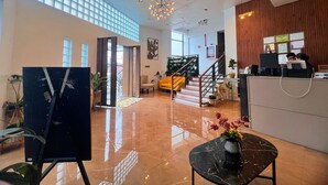 A spacious lobby with a high ceiling, a staircase, and a reception desk.