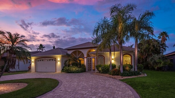 A residential house with a driveway, garage, and landscaped garden. - Solar Heated Pool, Hot Tub, Kayaks, Canal Views - Villa Tranquil Haven- Roelens Vacations (Cape Coral)