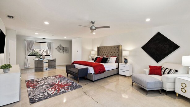 Un dormitorio moderno con cama, mesitas de noche, escritorio y una silla.