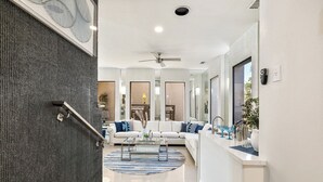 A modern living room with a sofa, coffee table, and a kitchen area with a sink and countertop.