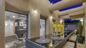 A modern interior with a glass-top table, wicker chairs, and a yellow lantern.