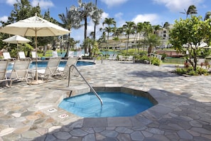 Un espace piscine comprenant plusieurs piscines, des chaises longues et des parasols.