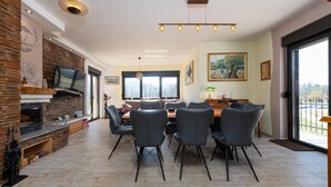 A modern dining area with a stone fireplace, a large TV, and a dining table with chairs. - Lovely home in Ornice (Ornice)