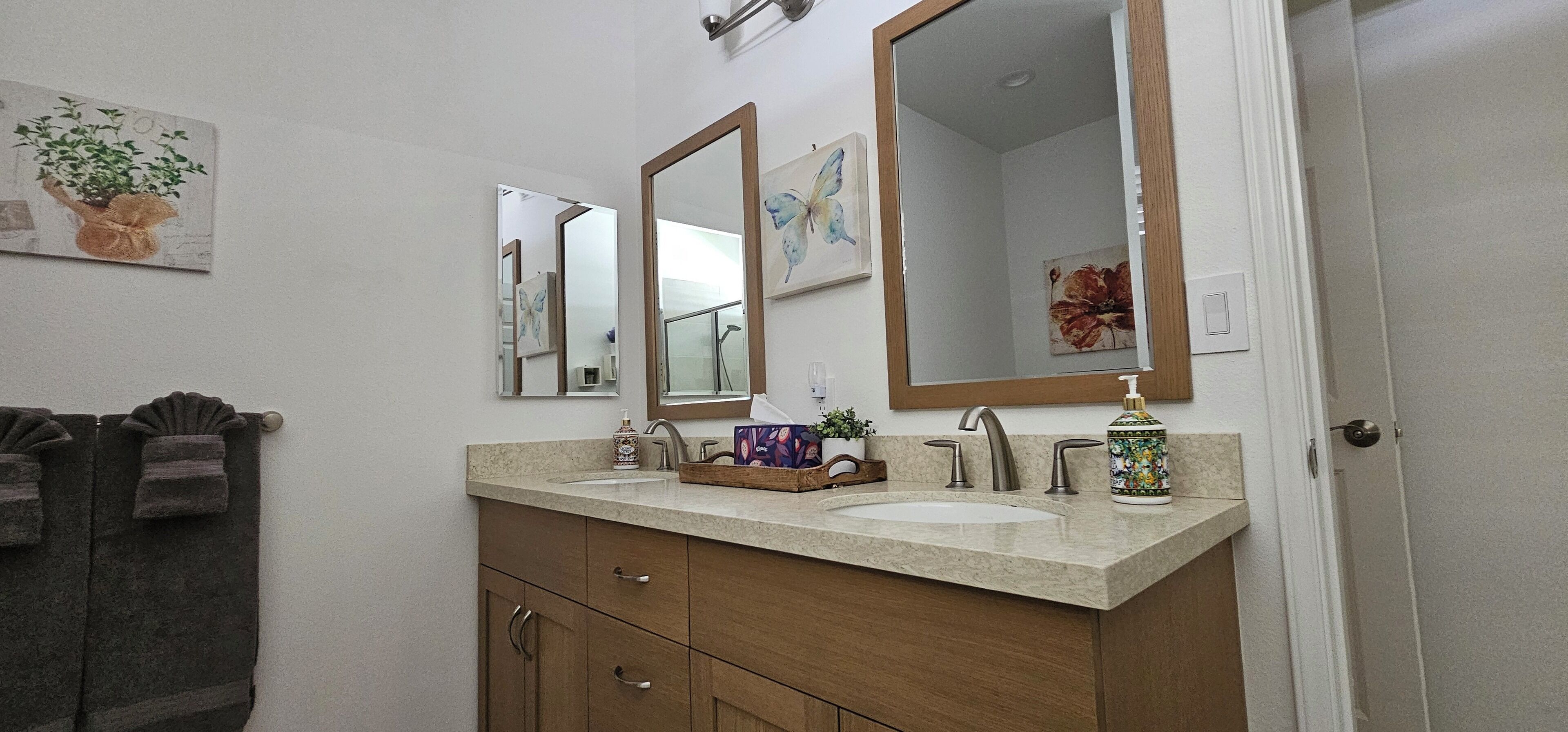 A bathroom with a double sink vanity, wooden cabinets, and a large mirror.