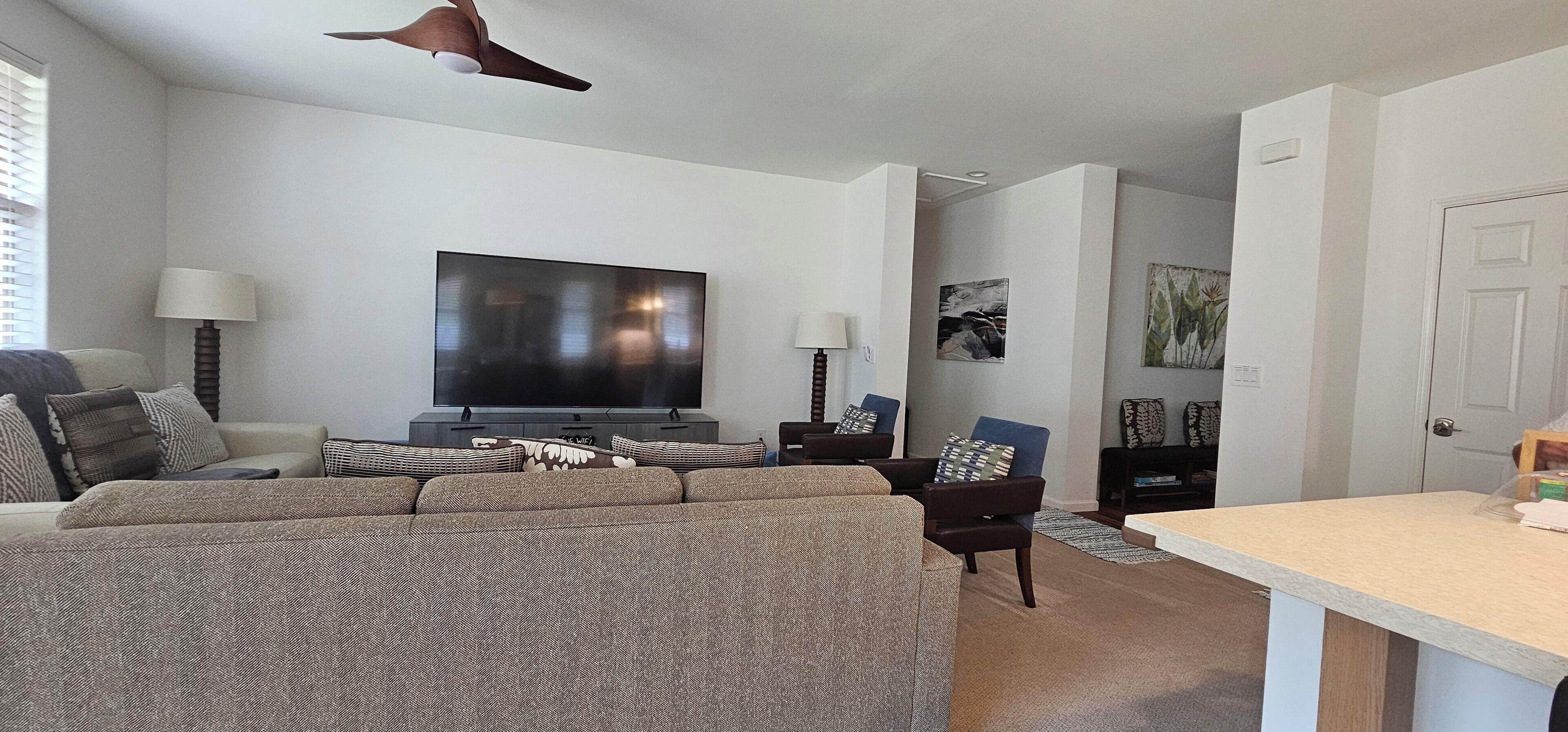 Ein modernes Wohnzimmer mit einem großen Flachbildfernseher, einer Couch, einem Sessel und einem Couchtisch.