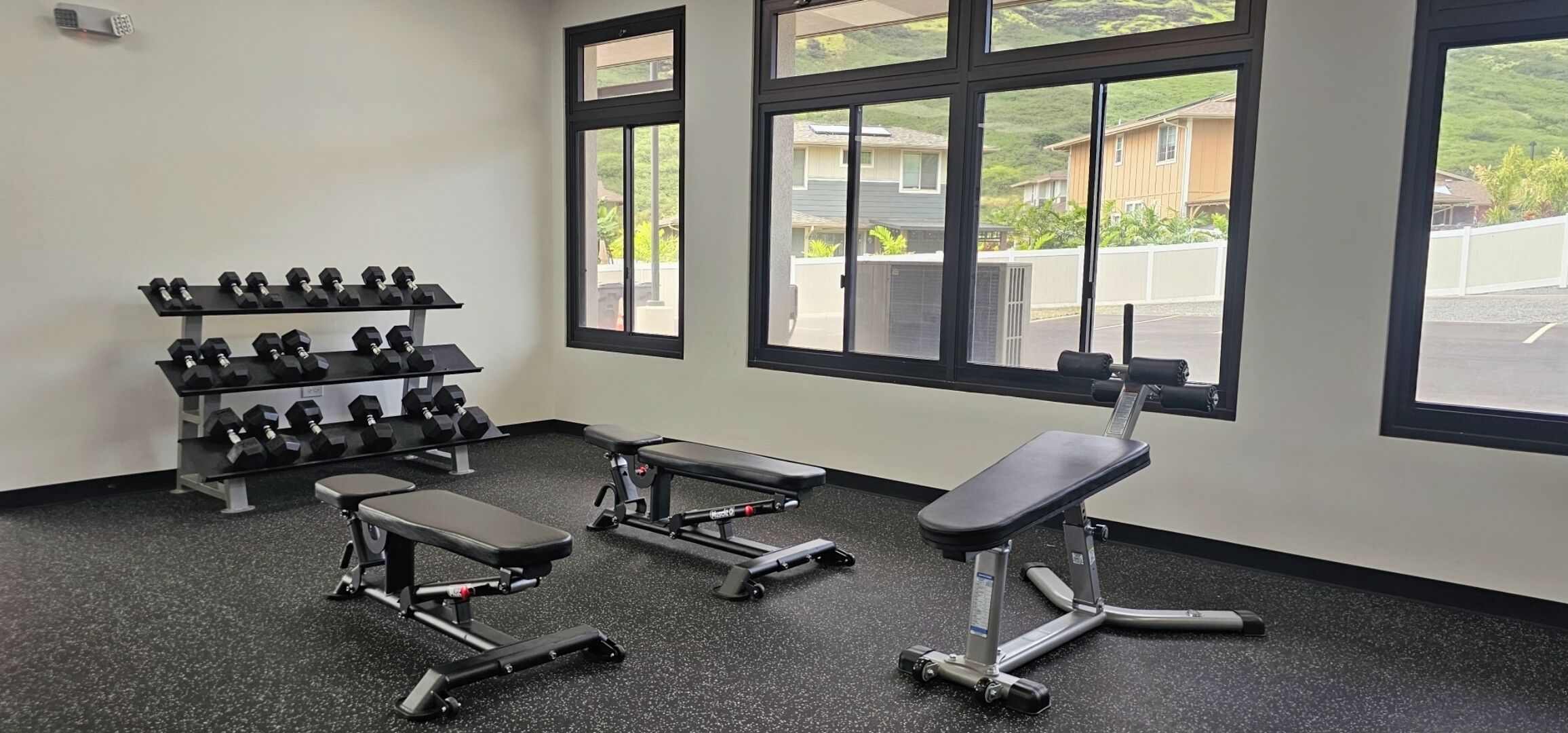 Une salle de sport équipée de bancs, d’haltères et d’un tapis de course.