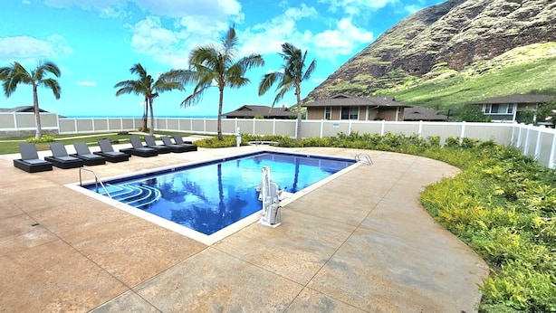 A swimming pool with lounge chairs, a poolside area, and a view of a mountain.