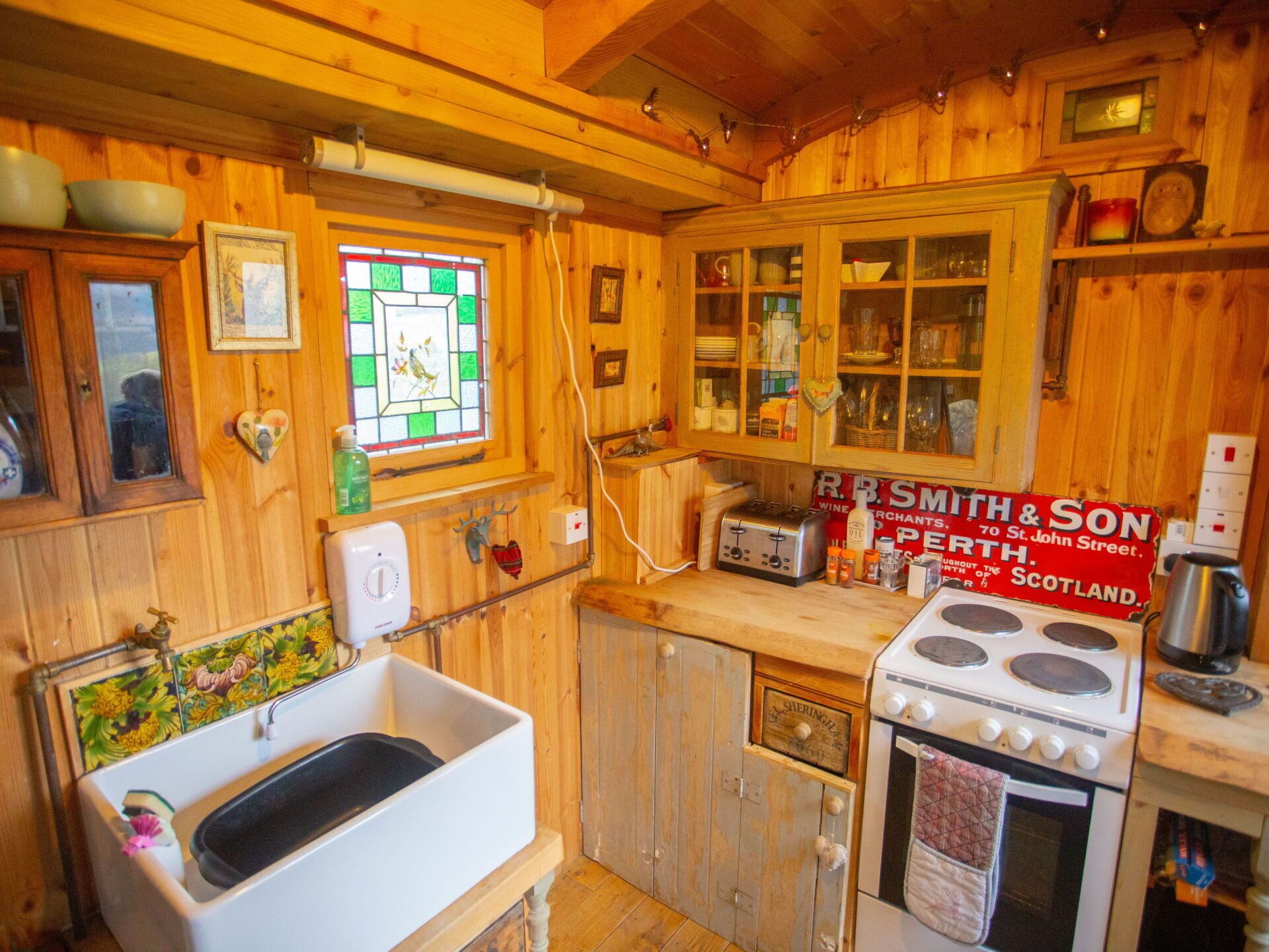Une cuisine rustique avec des meubles en bois, un poêle d’époque et un évier.