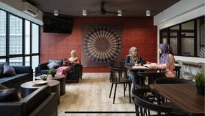 Un interior moderno con un gran tapiz de pared, un ventilador de techo y una zona de estar con mesas y sillas.