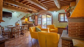A rustic interior with wooden beams, a dining area with yellow chairs, a kitchen with wooden cabinets, and a fireplace. - Private Villa with A/C, private pool, WIFI, patio, pets allowed, panoramic view, close to Cortona (Creti)