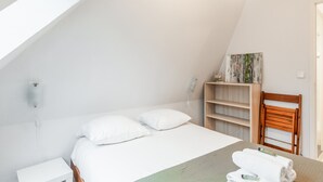 Ein Schlafzimmer mit einem Bett, einem Holzstuhl, einem Regal mit Dekoration und einem Bild an der Wand.