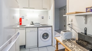 Eine kleine Küche mit Waschmaschine, Toaster und Esstisch.
