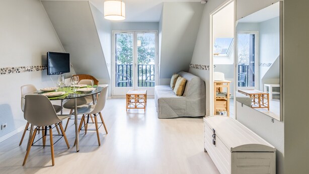 Ein moderner, gut beleuchteter Essbereich mit einem runden Tisch, Stühlen und einem an der Wand befestigten Flachbildfernseher.
