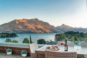 Eine Terrasse mit Tisch für zwei Personen mit Blick auf einen See und Berge.