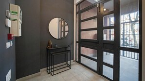 Un interior modern amb una gran porta corredissa de vidre, un mirall rodó i una petita taula consola negra.