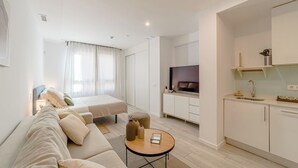 Un apartamento moderno con sala de estar, un dormitorio con ventana grande, zona de cocina y televisor.