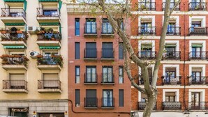 Un edificio de varios pisos con balcones, algunos con plantas.