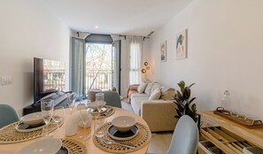 Ein modernes Wohnzimmer mit Essbereich, einer Couch und einem Fernseher.