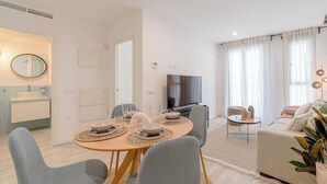 Un saló modern amb zona de menjador, un sofà i una televisió.