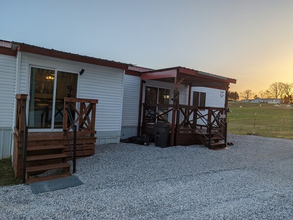A two-story building with a covered porch and a gravel driveway. - Cowboy Cottage (Florence)