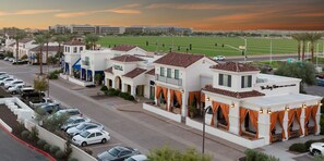 Un hotel con patio, mobiliario exterior y vistas a un campo deportivo.