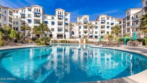 A resort with a central swimming pool, multiple-story buildings, and palm trees. - M'Cays Ocotillo! Patio Adore and More! 1 Month Min (Chandler)