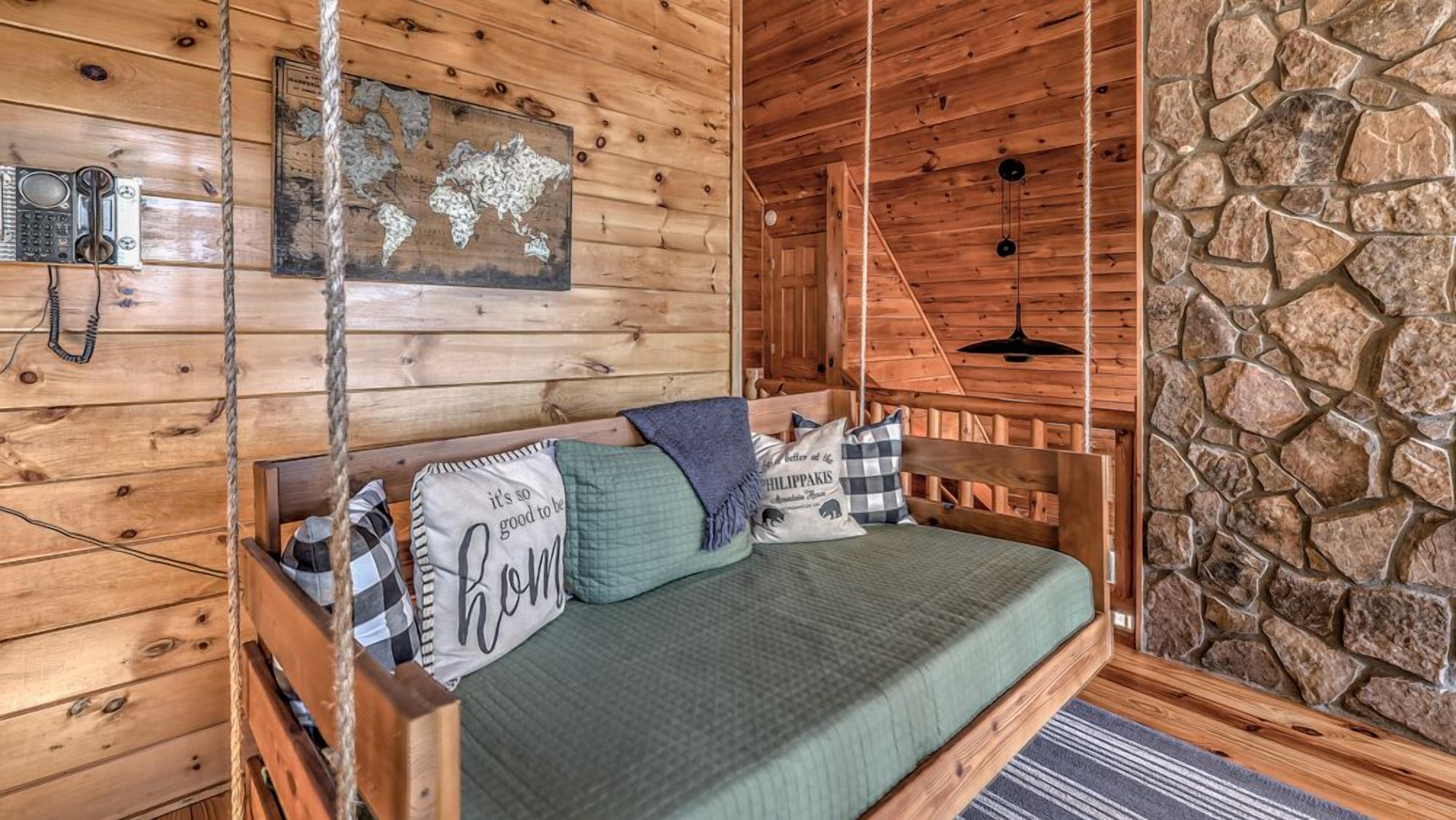 A wooden cabin room with a bed, a world map on the wall, and a stone wall.