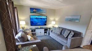 A living room with a sofa, a coffee table, a TV, and a bookshelf. - ^^Amazing Ocean View, Super Clean w/ Towels/Linen,1G WIFI @ Myrtle Beach Resort  (Myrtle Beach)