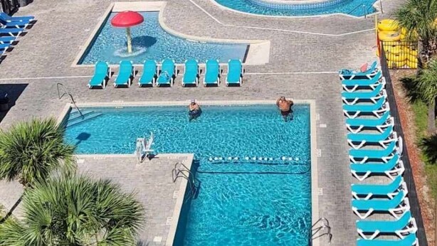 A swimming pool area with multiple pools, lounge chairs, and palm trees. - ^^Amazing Ocean View, Super Clean w/ Towels/Linen,1G WIFI @ Myrtle Beach Resort  (Myrtle Beach)
