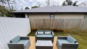 Eine Terrasse mit Korbmöbeln, darunter zwei Sofas und ein Couchtisch.