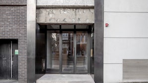 A building entrance with a glass door, a small step leading up, and a fire alarm on the right. - Modern Chelsea 1BR w/ Balcony nr shops, by Blueground (London)