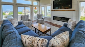 A spacious living room with a large TV, comfortable seating, and a fireplace.