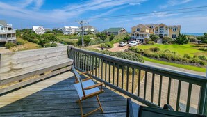 A wooden deck with a bench, overlooking a residential area with houses and a clear sky.