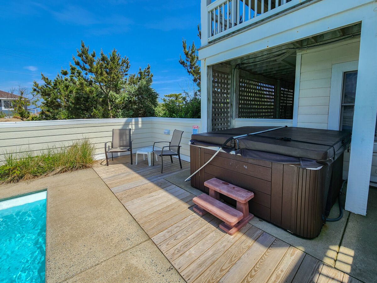 A backyard with a hot tub, a pool, and outdoor seating.