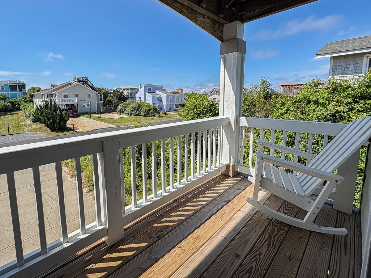 A wooden deck with a white railing and a rocking chair.