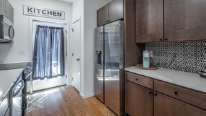 Eine moderne Küche mit Holzschränken, einem Edelstahlkühlschrank und einer ornamental gestalteten Spritzschutzwand.