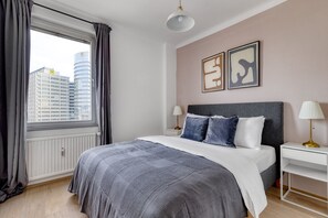 A modern bedroom with a large bed, a nightstand, a lamp, and artwork on the wall. - Stunning Innere Stadt 2BR w/ Roof & Elevator, nr U1/U4, by Blueground (Vienna)