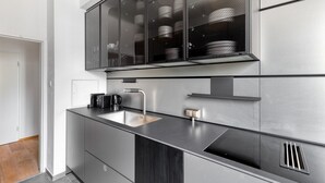 Una cocina moderna con un lavamanos de acero inoxidable, una cafetera y un horno empotrado.
