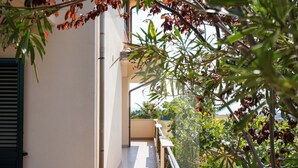 Un balcone con vista su un edificio e vegetazione circostante.