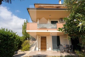 A two-story house with a balcony, a door, and outdoor furniture. - Villa Mila with beautiful sea view (Pineto)